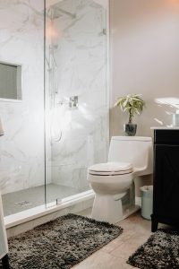 Baño con enchape de mármol y ducha de vidrio