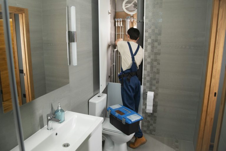 Servicio de gasfitería: gasfitero reparando la tubería de un baño